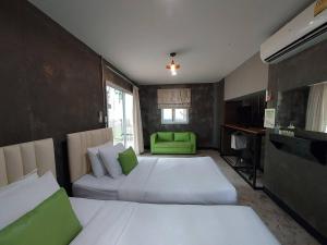 a bedroom with two beds and a green chair at ปานีวิลล์ รีสอร์ต in Ban Wang Takhrai