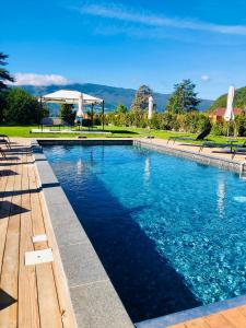 una piscina con agua azul y bancos de madera en Hôtel Le Mouton Bleu en Talloires