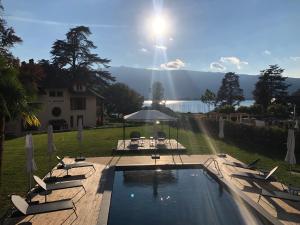 a pool with chairs and a table and the sun at Hôtel Le Mouton Bleu in Talloires