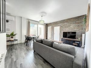ein Wohnzimmer mit einem Sofa und einem TV in der Unterkunft Appart T3 LE PATIO - avec terrasse in Boujan-sur-Libron