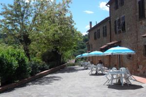 grupa stołów i parasoli na patio w obiekcie RELAIS Le Querciole w mieście Montaione