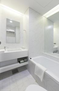 Baño blanco con bañera y lavamanos en StayB Hotel Myeongdong, en Seúl