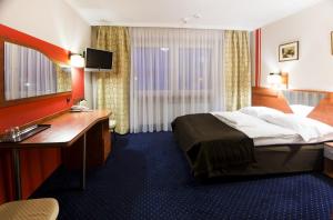 Una habitación de hotel con una cama, un escritorio y un lavabo. en Hotel Orion, en Sosnowiec 79 fotos más