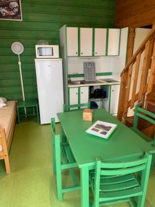 una mesa verde y sillas en una cocina con nevera en Camping municipal de la Lande, en Nexon