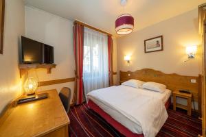 a hotel room with a bed and a desk and a television at Hôtel du Parc, Restaurant, Spa & Wellness in Niederbronn-les-Bains