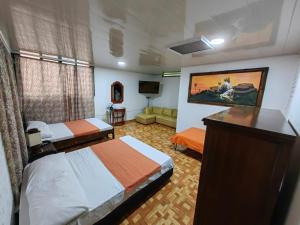 una camera d'albergo con due letti e una televisione di Hospedaje Rancho Guadalupe a La Suiza