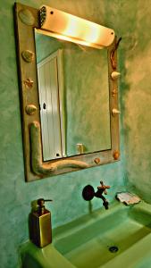 a bathroom with a mirror and a green sink at Ethereal Apartments in Agrari