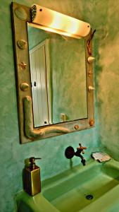 bagno con specchio e lavandino verde di Ethereal Apartments ad Agrari