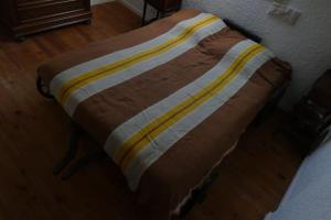 a bed with a striped blanket on top of it at Gîte Mémoire de cœur 14 pers in Foucherans