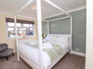 a bedroom with a white bed and a chair at Prestella in Filey