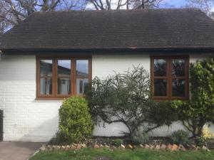 ein weißes Haus mit zwei Fenstern darauf in der Unterkunft Cute Cottage 2024 Traveller Award in Yateley