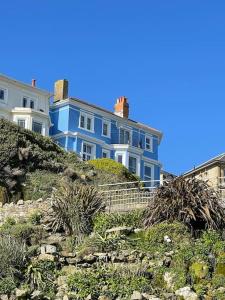 a blue house sitting on top of a hill at Top Deck - Fresh, stylish seaside apartment in Ventnor