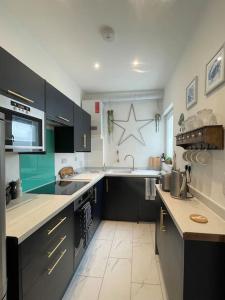 a kitchen with black cabinets and a white floor at Top Deck - Fresh, stylish seaside apartment in Ventnor
