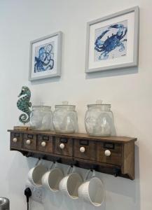 un estante con tazones de vidrio y placas en una pared en Top Deck - Fresh, stylish seaside apartment, en Ventnor