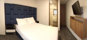 a bedroom with a bed with a blue headboard and a television at Hotel Everest Chia Oficial in Chía