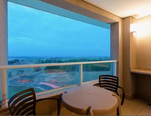 a room with a table and chairs and a large window at Apartamento Resort Solar das Águas em Olímpia in Olímpia