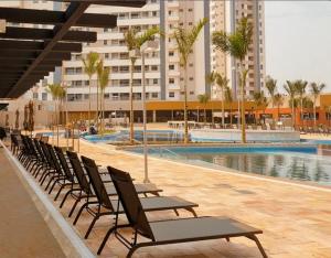 a row of chairs next to a swimming pool with a building at Apartamento Resort Solar das Águas em Olímpia in Olímpia