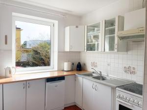 biała kuchnia ze zlewem i oknem w obiekcie Casa Verano by 3City Rentals w mieście Gdynia