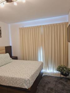 a bedroom with a bed and a window with curtains at Edificio Leonardo 6to piso in Villa Carlos Paz