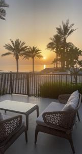 eine Terrasse mit 2 Stühlen, einem Tisch und Palmen in der Unterkunft Address beach resort fujairah in Ḩaqīl