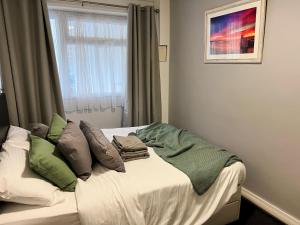 1 dormitorio con cama con almohadas y ventana en Beach Court Ground Floor - Cosy Apartment with Sea Views, en Saundersfoot