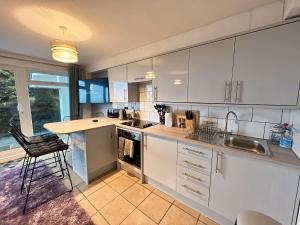 a kitchen with white cabinets and a sink and a counter at Beach Court Ground Floor - Cosy Apartment with Sea Views in Saundersfoot
