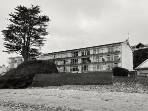 un grand bâtiment avec un arbre en face dans l'établissement Beach Court Ground Floor - Cosy Apartment with Sea Views, à Saundersfoot