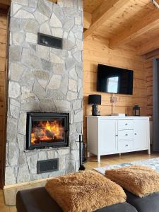 a fireplace in a living room with a stone wall at Dom na Zielonym Wzgórzu z własną Sauną i Jacuzzi in Łapsze Niżne