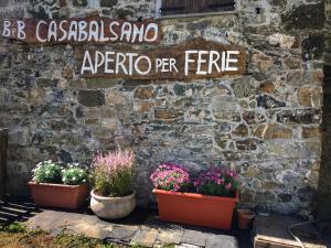 a stone wall with three potted plants and a sign at Casa Balsamo in Borzonasca