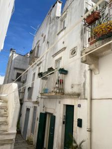 a white building with green doors and a balcony at Residenza Le Tre Volte - colazione inclusa con TicketBar in Martina Franca