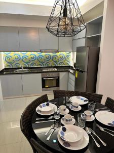 uma cozinha com uma mesa preta com pratos e talheres em The Pearl Interior Designed 1 BR Unit Burgos Circle BGC em Manila