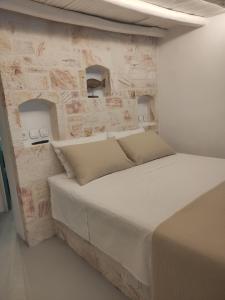 a bed in a room with a stone wall at Apanemo Beach House Agios Nikolaos Kimolos in Kimolos