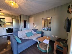 ein Wohnzimmer mit einem blauen Sofa und einer Küche in der Unterkunft Stella in Arès
