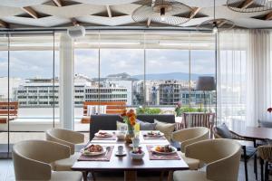 comedor con mesa y sillas y ventana grande en Wyndham Athens Residence, en Atenas