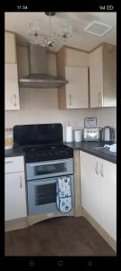 a kitchen with a stove and white cabinets at N and B caravan hire Flamingo Land in Kirby Misperton