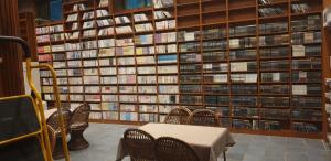 a room with a table in front of a wall of books at The Red House in Sokcho
