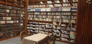 uma biblioteca com mesa e cadeiras e prateleiras de livros em The Red House em Sokcho