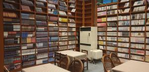 uma biblioteca com mesas e cadeiras em frente a uma parede de livros em The Red House em Sokcho