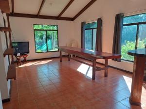 a dining room with a wooden table and windows at House Manantial de Vida in Nandayure