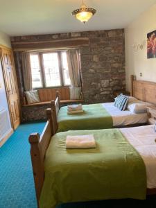 una camera d'albergo con tre letti con lenzuola verdi di The George Inn & Millingbrook Lodge Ltd a Lydney