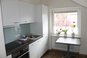 a kitchen with white cabinets and a sink and a window at Blick ins Grüne in Überlingen