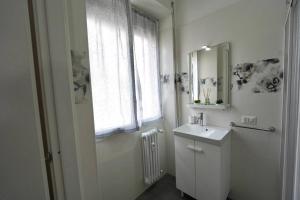a white bathroom with a sink and a window at Cinecittà Luxury Flat Metro A in Rome
