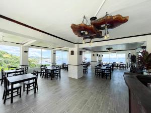 uma sala de jantar com mesas, cadeiras e janelas em Ocean View Hotel and Restaurant em Roatan