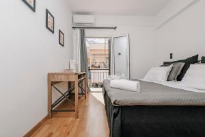 a bedroom with a bed and a table with a window at Avenue Apartment Corfu Town in Ágios Rókkos