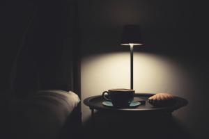 a coffee cup and a lamp on a table next to a bed at Avenue Apartment Corfu Town in Ágios Rókkos