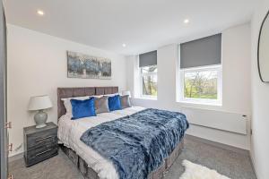 ein Schlafzimmer mit einem großen Bett mit blauen Kissen in der Unterkunft Charles House Serviced Apartments in Preston