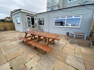 a picnic table and benches on a patio with a house at The Calder House Hotel in Seascale