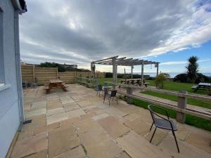 a patio with chairs and tables and a wooden fence at The Calder House Hotel in Seascale