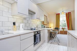 eine Küche mit weißen Schränken und einer Arbeitsplatte in der Unterkunft Fabulous 5 Double Bedroom Edinburgh Old Town apartment in Edinburgh