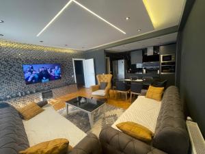 a living room with a couch and a tv at Sonny’s Penthouse in Gjilan